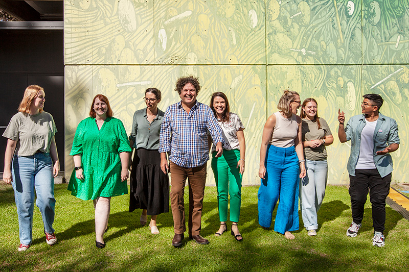 Eight people laughing and walking in green grass